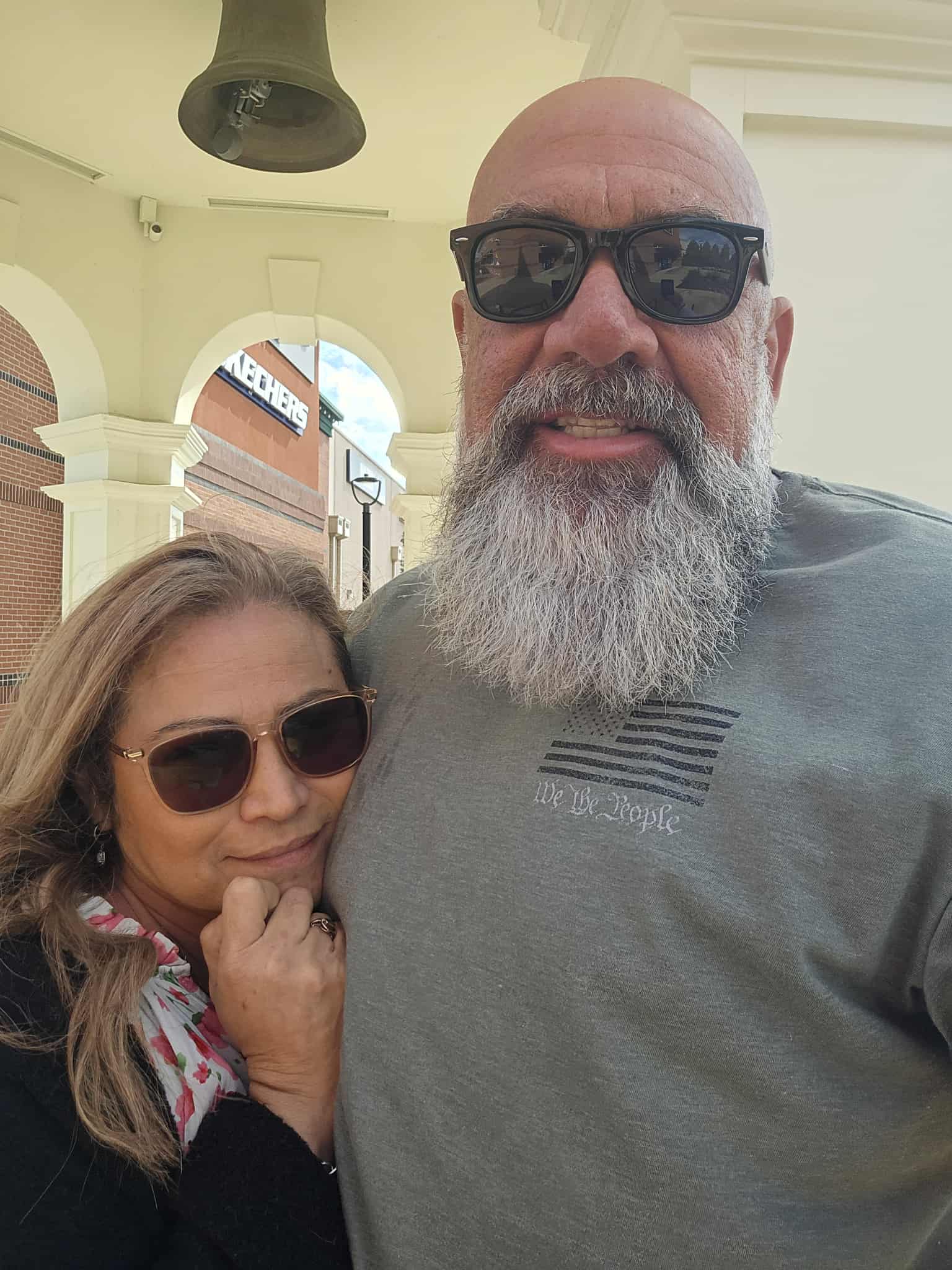 Hammer and his wife in casual attire with sunglasses, looking relaxed and happy