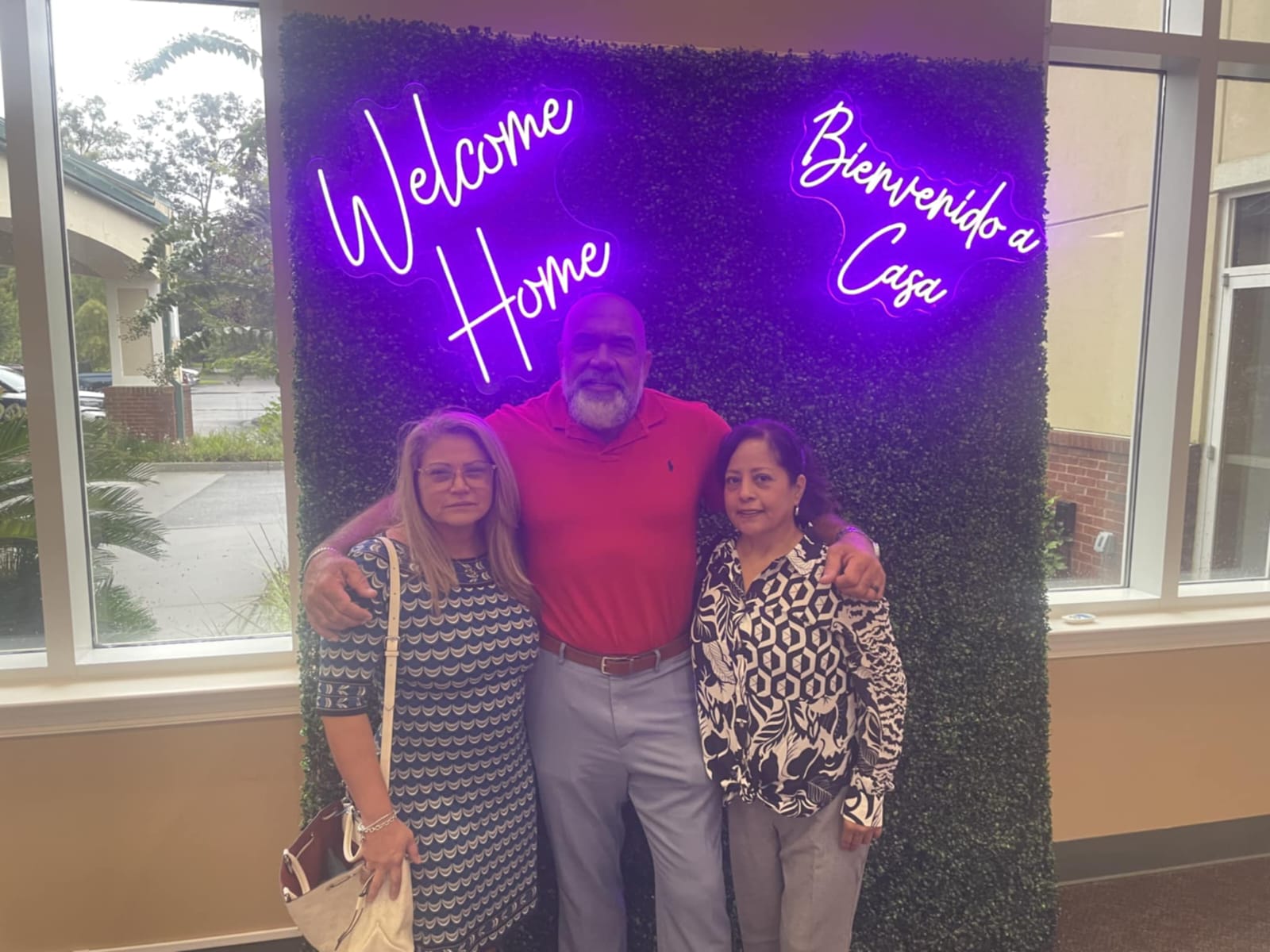 Hammer with family members in front of a Welcome Home neon sign